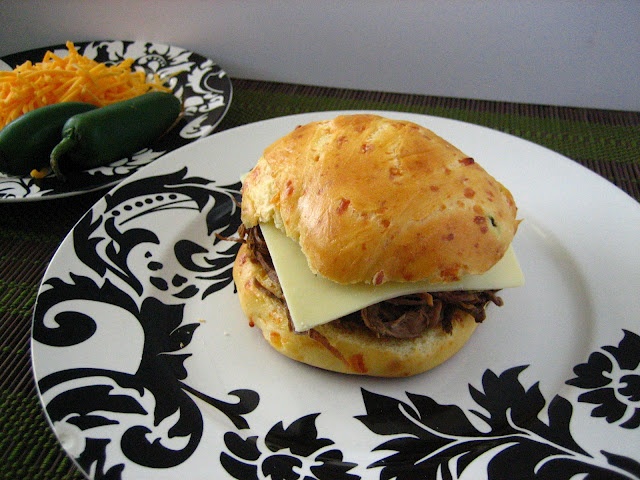 a sandwich with cheese and meat is on a black and white plate next to other plates