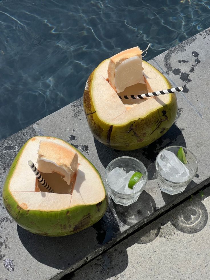 two pieces of fruit sitting on top of a table next to a pool with water in it