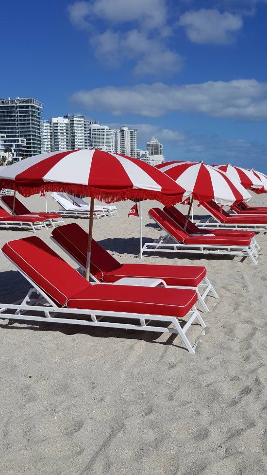 lounge chairs and umbrellas are lined up on the beach