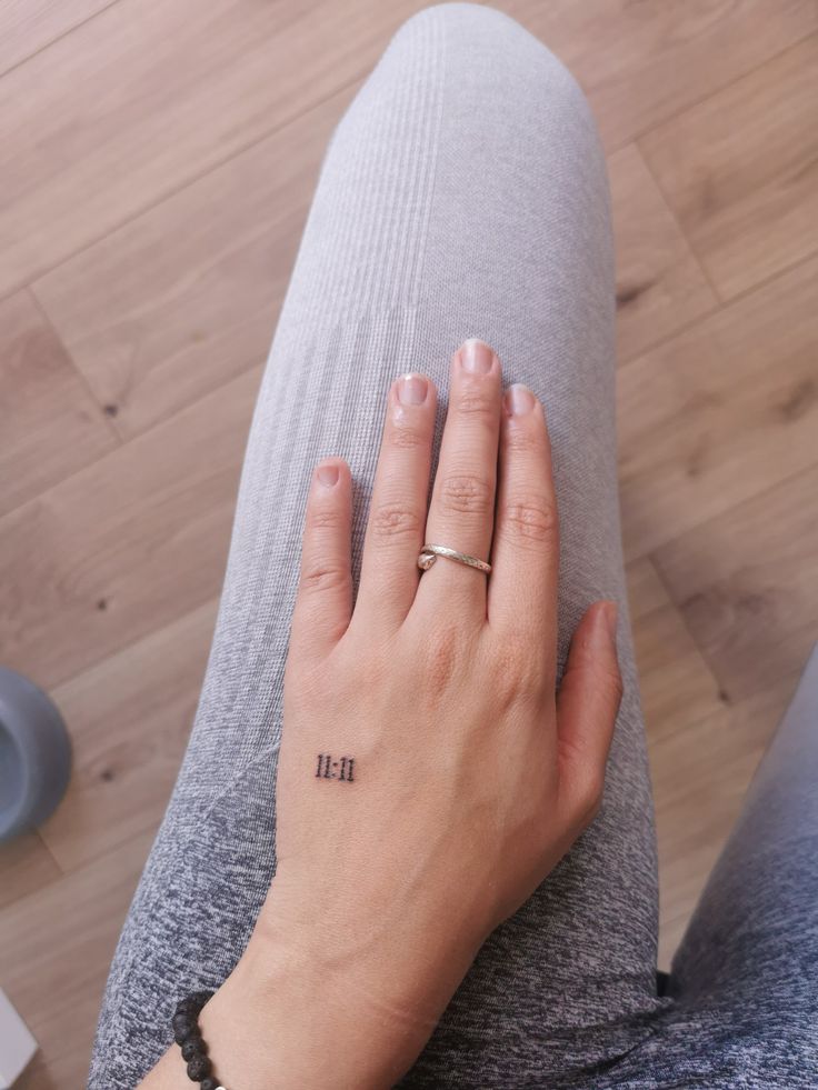 a woman's hand with a small tattoo on her left wrist, sitting on the floor