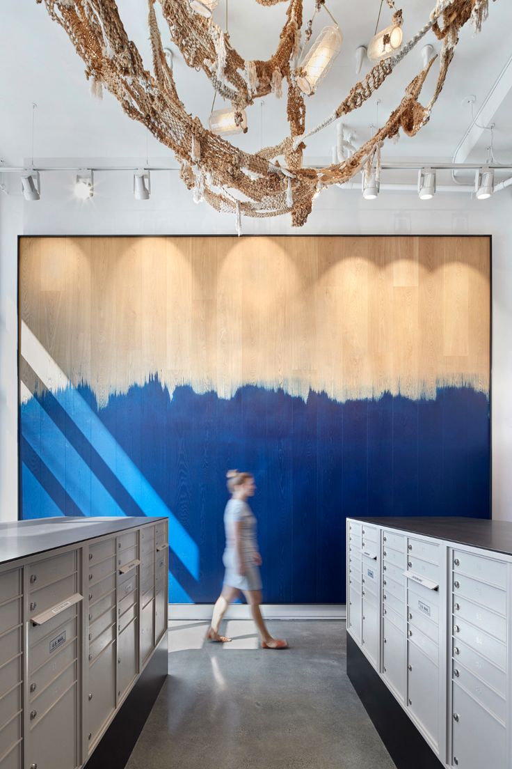 a person walking down a hallway in front of a blue and white painting on the wall