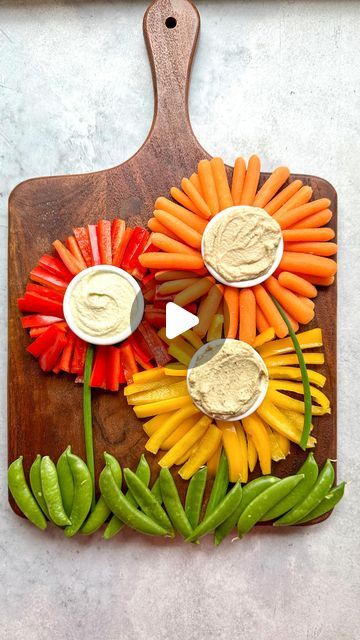 a cutting board with vegetables and dips on it