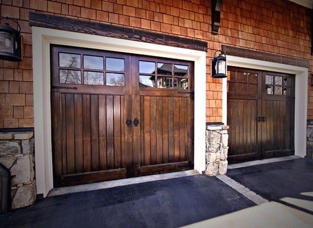 two brown garage doors are open in front of a brick building with lanterns on the side