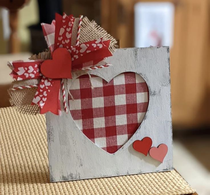 a heart shaped box with red and white paper hearts on the front sitting on top of a table