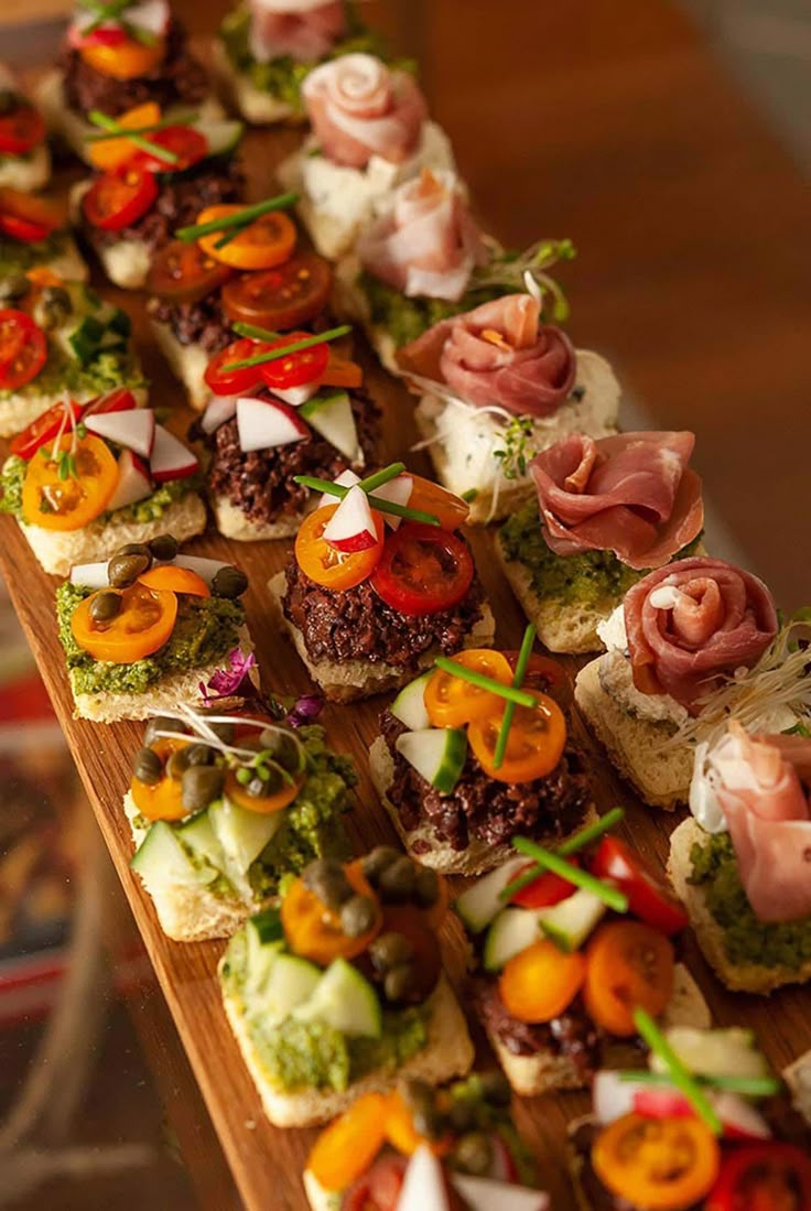 a wooden table topped with lots of different types of appetizers on top of it