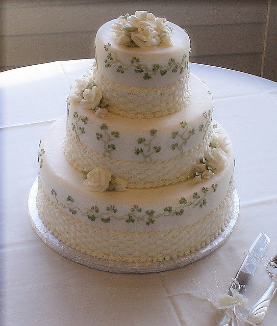 a three tiered wedding cake sitting on top of a white tablecloth covered table