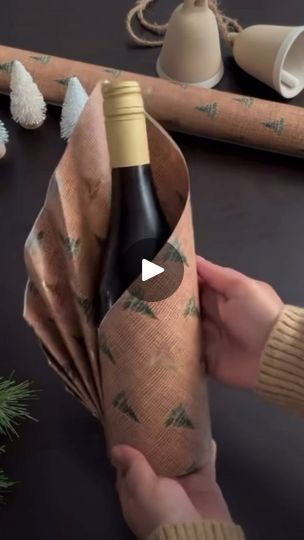 someone holding a bottle of wine in front of christmas decorations and other items on a table