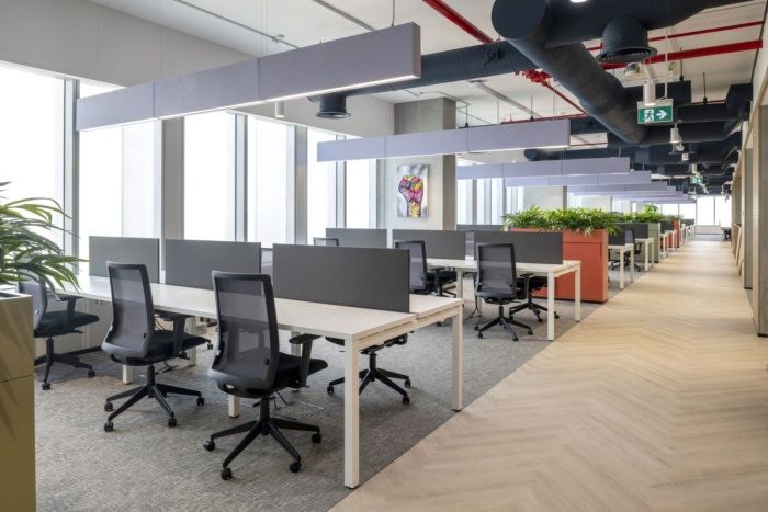 an office with desks, chairs and plants in the middle of the floor area