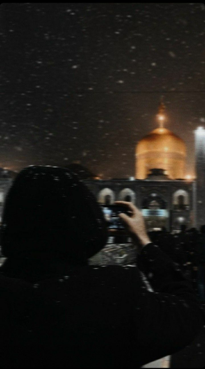 a person taking a photo with their cell phone in front of a building at night