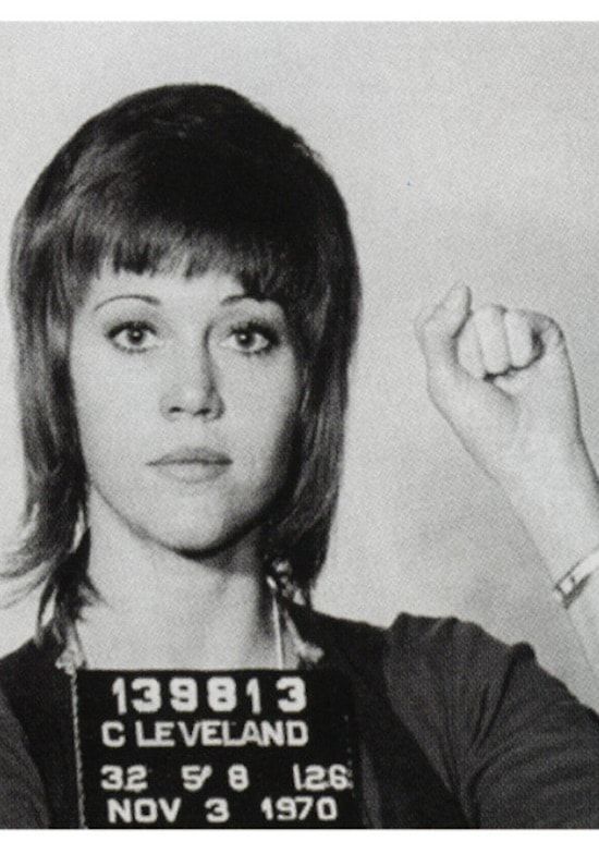 a mug shot of a woman holding her fist up