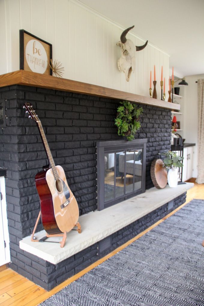 a living room with a fireplace and guitar on the mantel in front of it