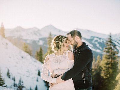 a man and woman standing next to each other on top of a snow covered slope