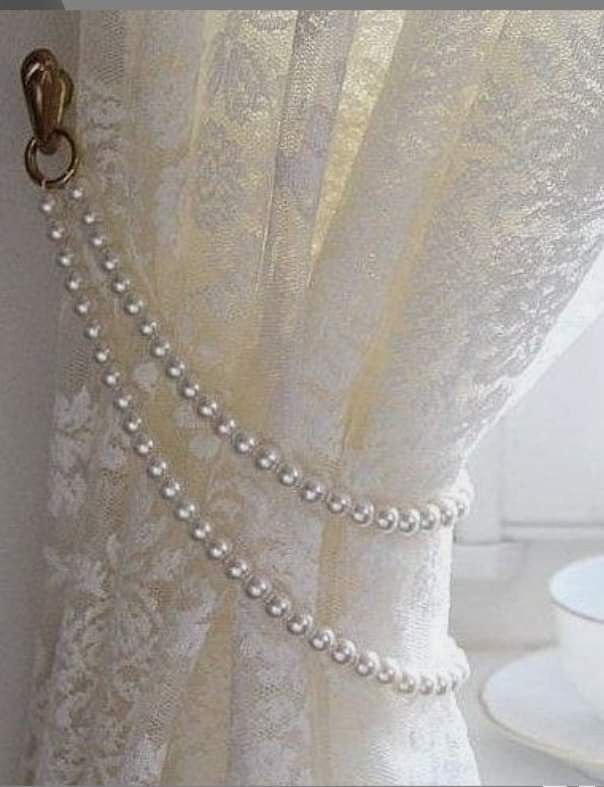 a curtain with pearls attached to it next to a cup and saucer on a table