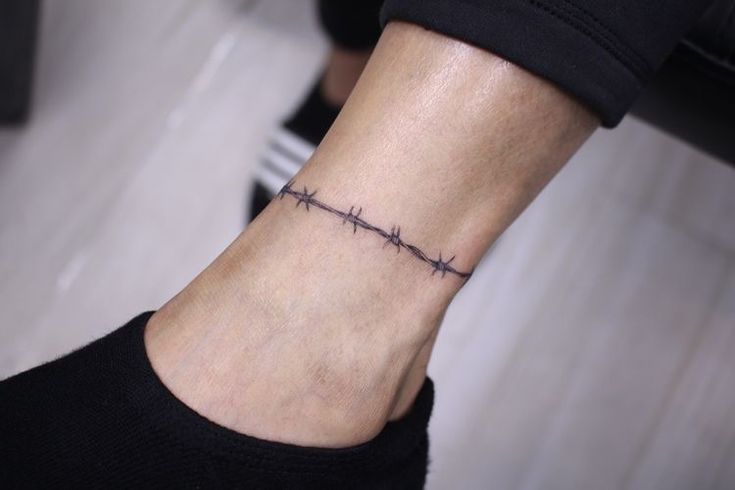 a woman's ankle with a barbed wire tattoo on it