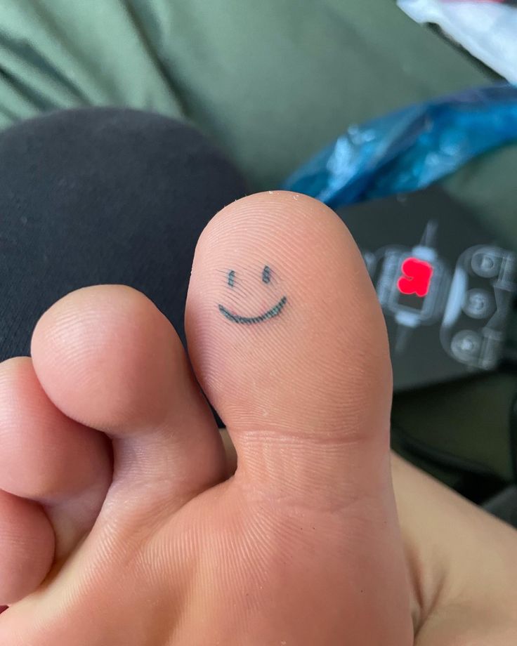 a person's foot with a smiley face drawn on the middle of their toe