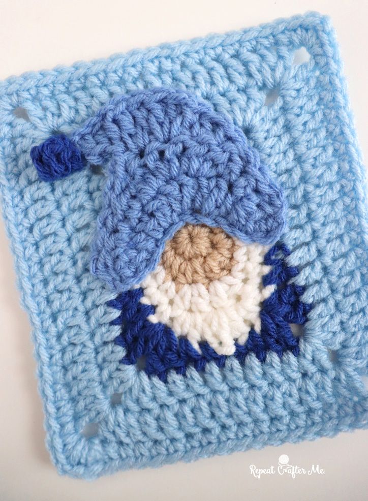 a crocheted square with a blue and white bird on the center is shown