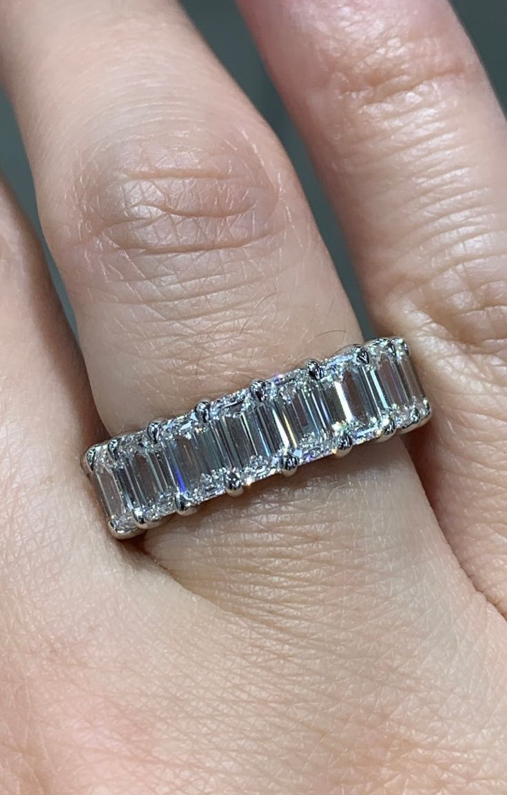 a woman's hand with a diamond ring on top of her finger and an engagement band in the middle