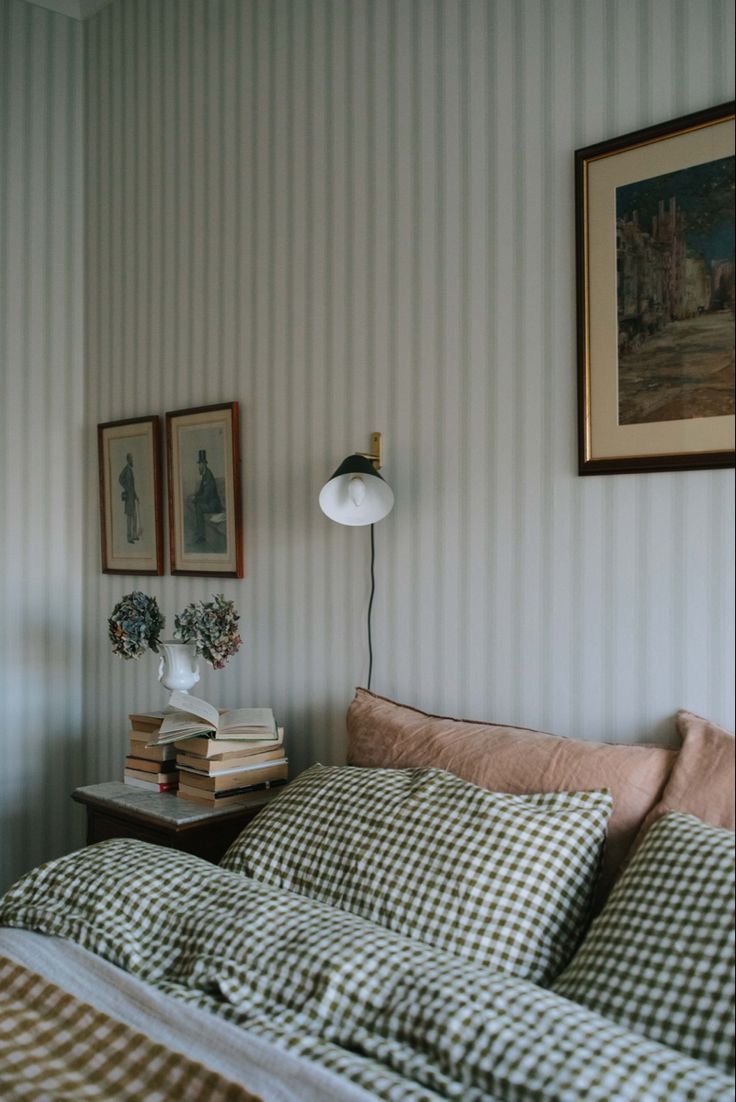 a bed sitting in a bedroom next to a lamp and pictures on the wall above it