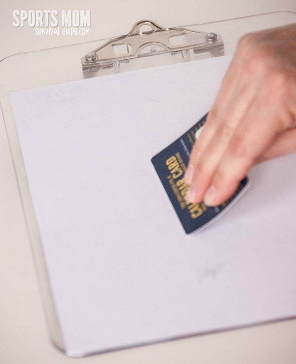 a person's hand on top of a clipboard with a credit card stuck to it