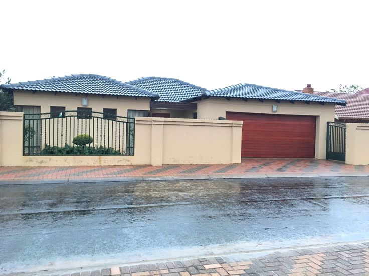 a couple of houses sitting next to each other on a wet street in front of a fence