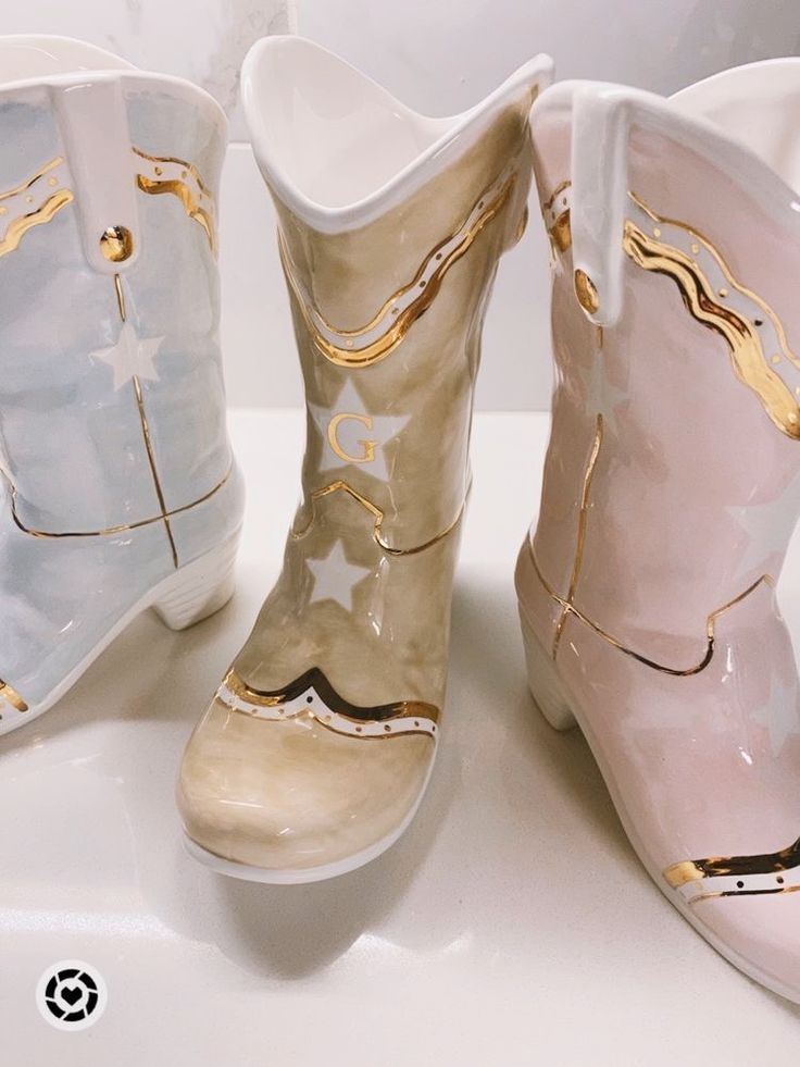 three pairs of cowboy boots with gold and white designs on the inside, one is pink