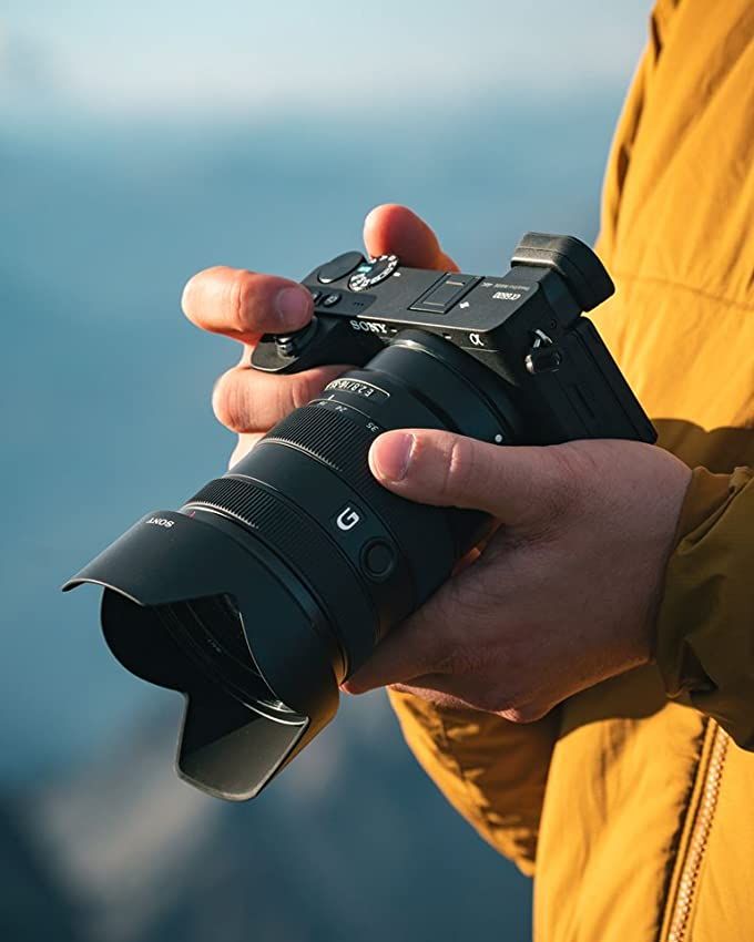 a person holding a camera in their hand with the lens attached to it's body