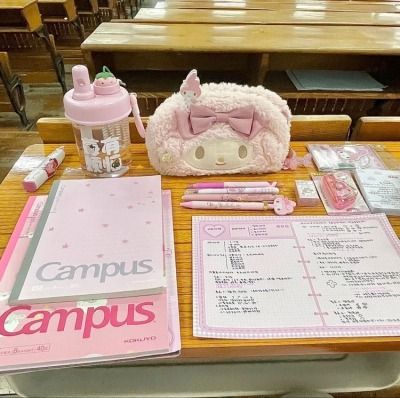 a table with pink items on it in a school setting, including notebooks and pens