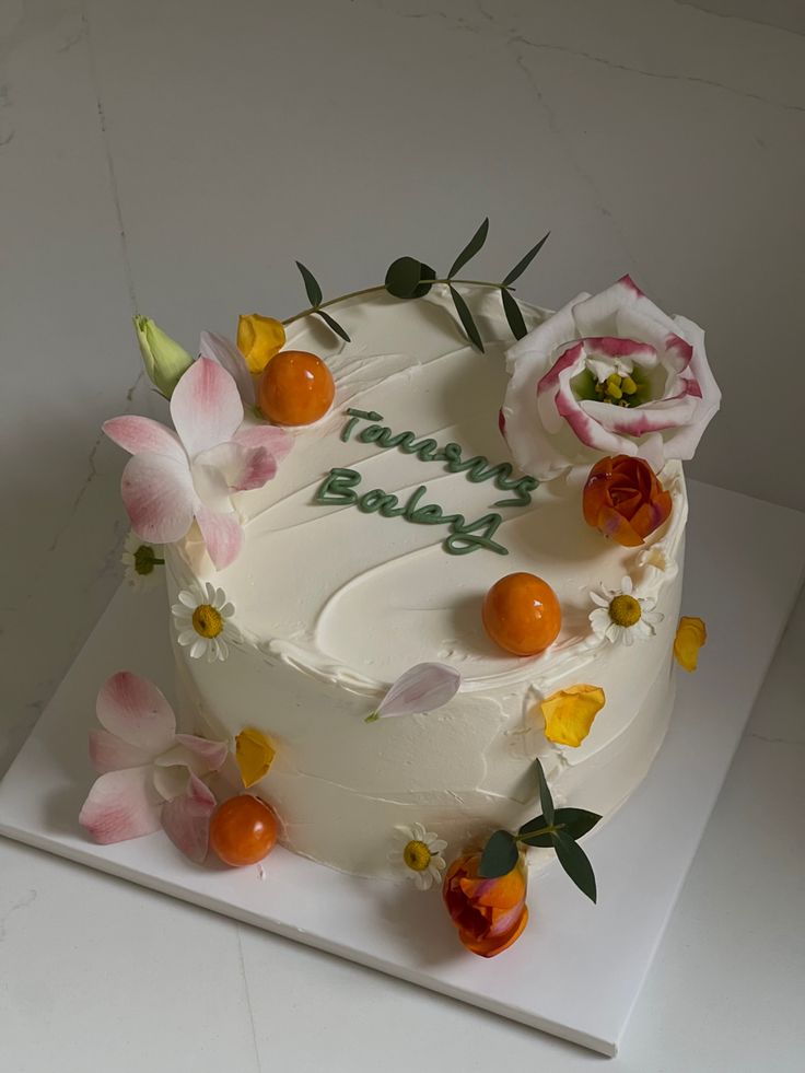 a birthday cake decorated with flowers and fruit