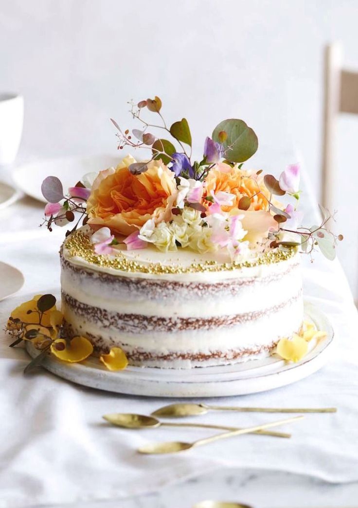 there is a cake with flowers on it and gold spoons next to the cake