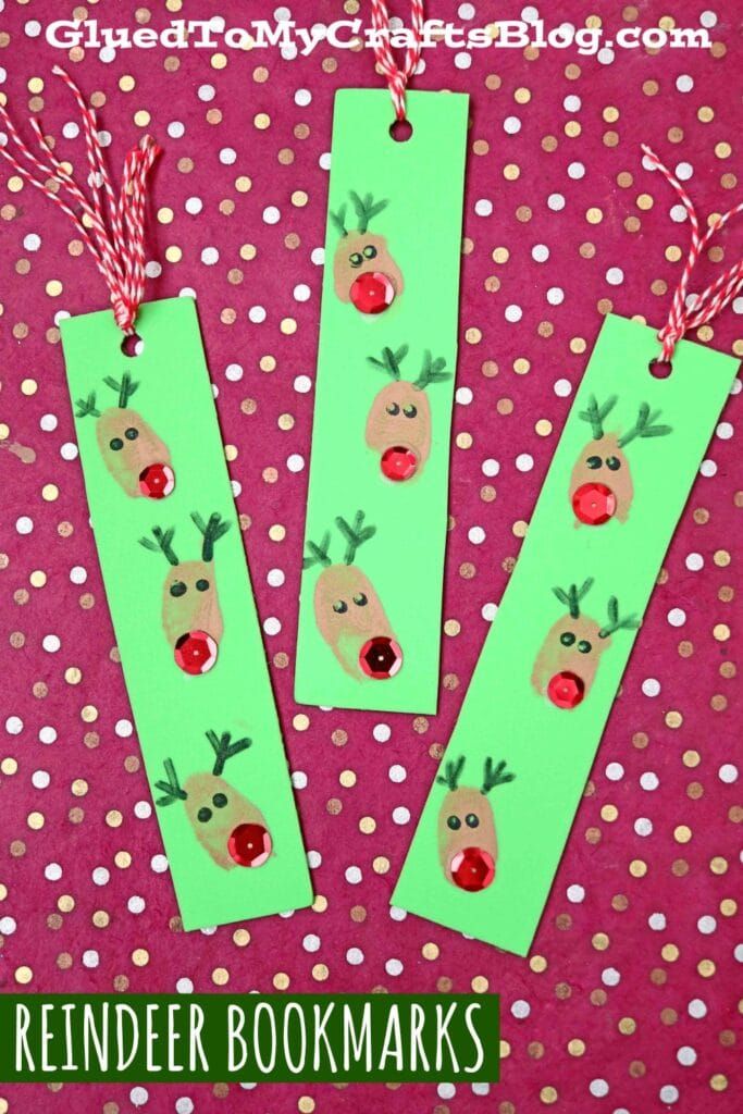 three bookmarks with reindeer faces on them and red string hanging from the top, in front of a polka dot background