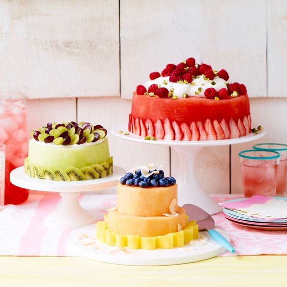 there are three cakes on the table and one is decorated with berries, raspberries, and other toppings