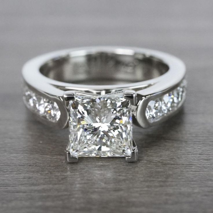 a white gold ring with a princess cut diamond in the center and side stones on each band