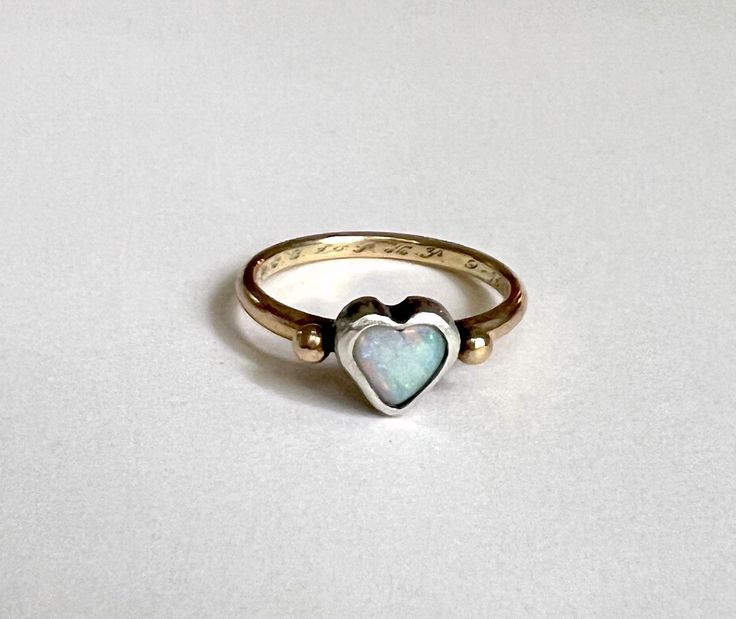 This darling one of a kind ring features a beautiful Australian opal heart which I set in a chunky handmade sterling silver bezel. It sits perched atop a heavy fun round 14k yellow antique reclaimed wedding band, which has an engraving of 9-15-56 along with initials in cursive. I melted two little gold pebbles from scrap and flanked the stone with them. I oxidized the silver bezel to a darker black finish, to contrast with the stone and the yellow gold. One Of A Kind Heart Jewelry For Anniversary, Heirloom Opal Ring With Polished Finish Gift, Unique White Gold Opal Ring Gift, One-of-a-kind Opal Jewelry For Anniversary, Heirloom White Gold Opal Ring As A Gift, Heirloom White Gold Opal Ring Gift, Heart Shaped Opal Jewelry For Anniversary, Handmade 14k Gold Opal Ring For Anniversary, One Of A Kind Opal Ring For Anniversary