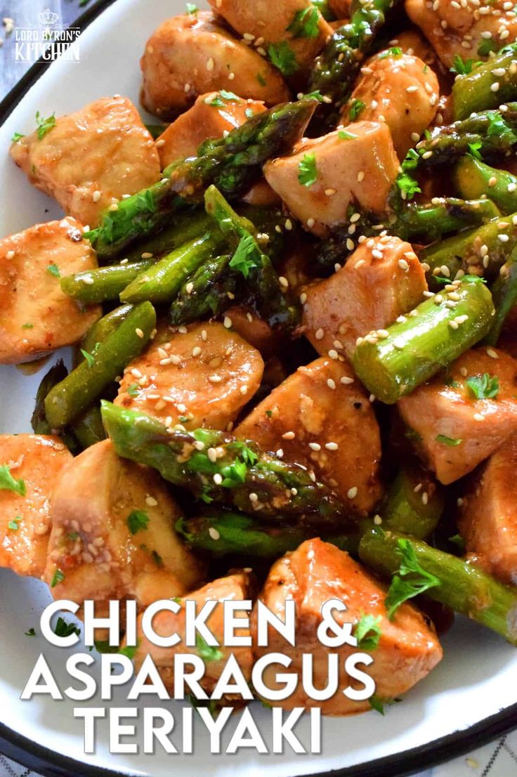 a white plate topped with chicken and asparagus covered in sesame seed sauce on top of a table