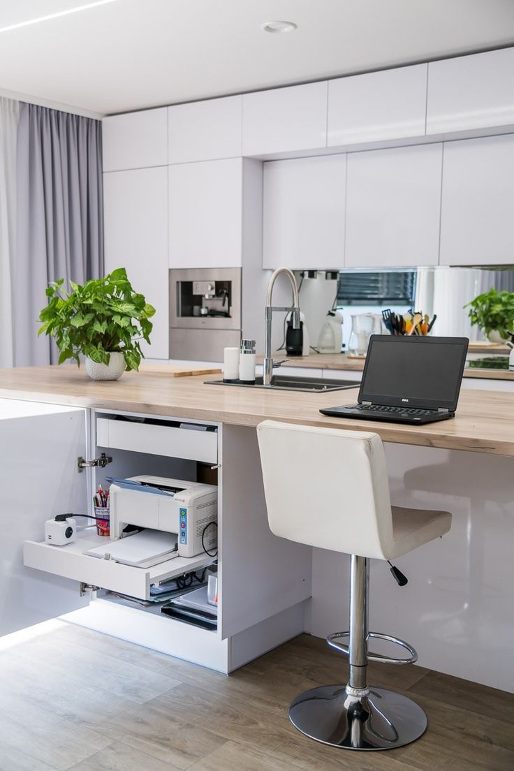 a laptop computer sitting on top of a kitchen counter next to a bar with stools