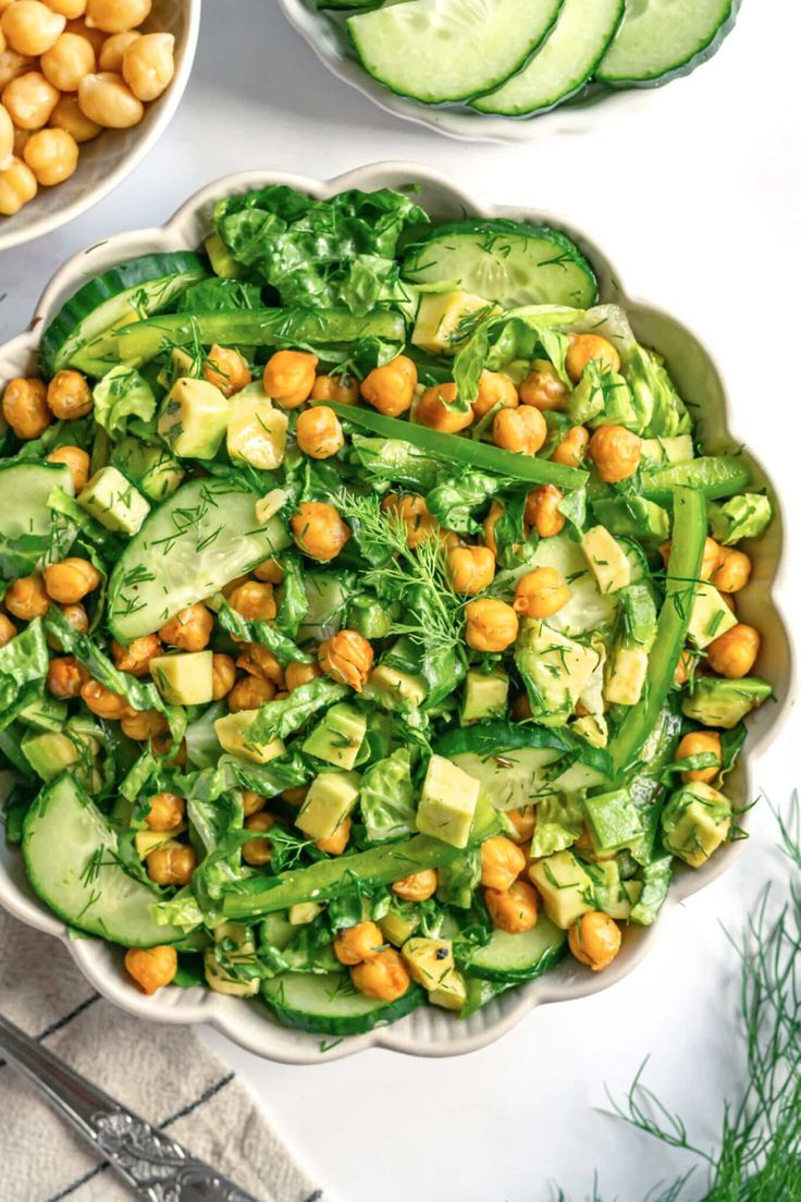 two bowls filled with cucumber and chickpeas next to some sliced cucumbers