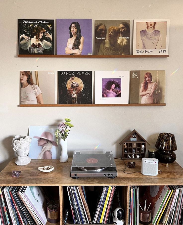 a record player sitting on top of a wooden table next to a shelf filled with records