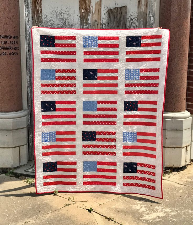 an american flag quilt hanging on the side of a building