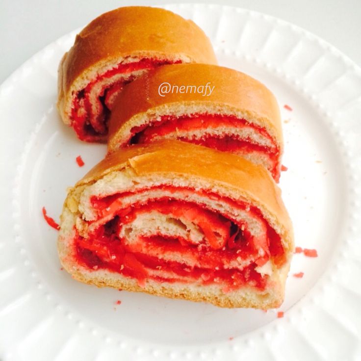 there is a sandwich that has been cut in half on a white plate with red sauce