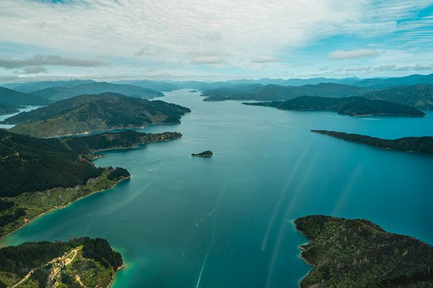 an aerial view of several islands in the ocean with blue water and green hills around them