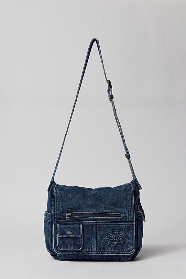 Essential messenger bag crafted from premium BDG denim. Low-profile silhouette with a pocketed flap closure. Lined interior with two pockets and plenty of space for your essentials. Complete with a zip pocket at the back for easy access, plus a water bottle pocket at the side. Finished with an adjustable strap - wear it on your shoulder or crossbody. Urban Outfitters exclusive. Features BDG denim messenger bag Washed soft denim with tons of storage Plenty of pockets inside and out Water bottle p Messenger Bag With Water Bottle, 90s Messenger Bag, Cute Everyday Bags, What’s In My Messenger Bag, Grunge Messenger Bag, Cute Bags For School, Jean Pocket Purse, Cute Bags And Purses, Denim Jean Purses