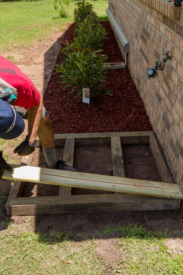 a man is working on the side of a brick building with wood planks attached to it