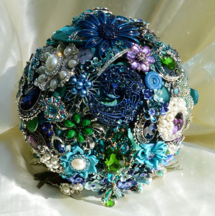 a bridal bouquet made up of beads and other jeweled items on a white cloth