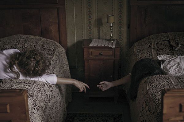 two people are lying in twin beds and reaching for each other's hand with their hands