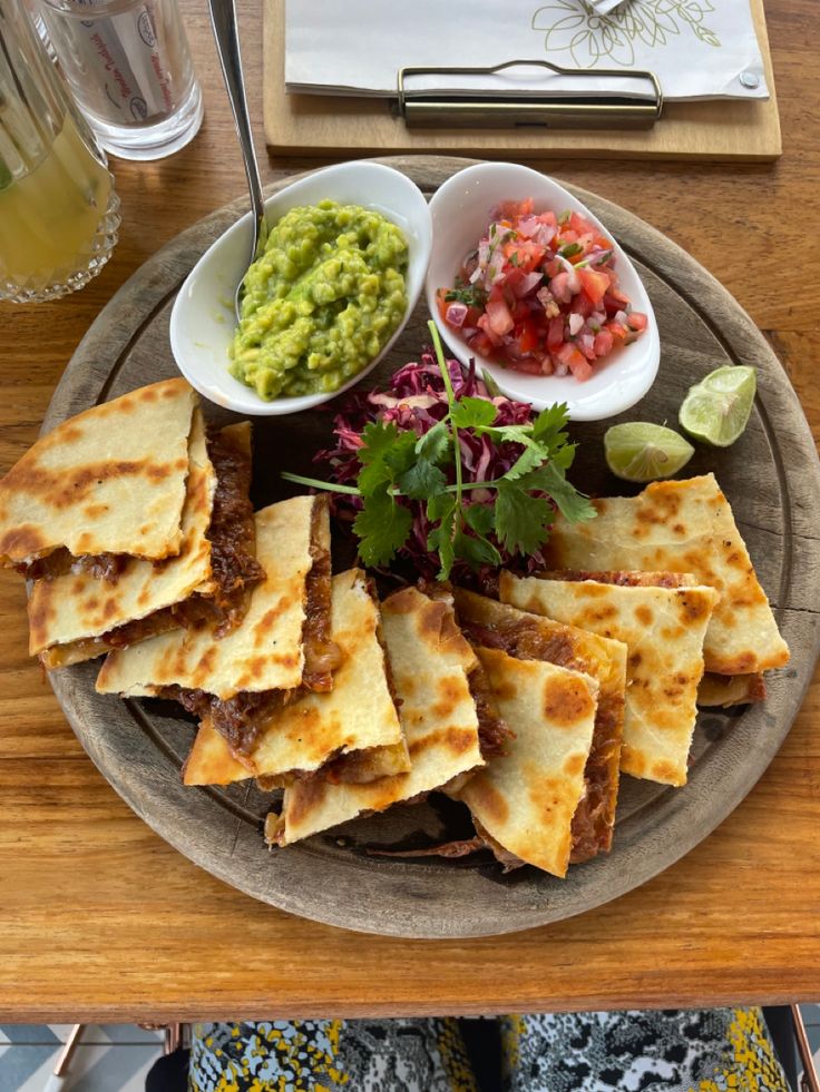 a plate with tortillas, salsa and guacamole on the side