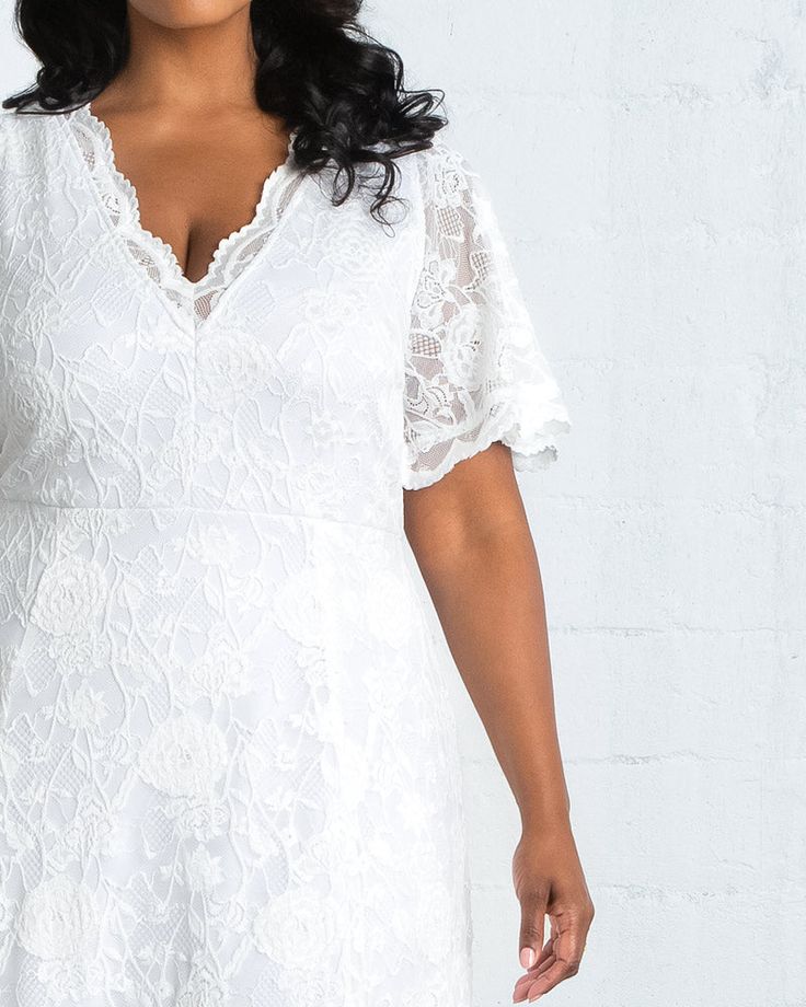 a woman wearing a white lace dress with short sleeves and an open v - neck