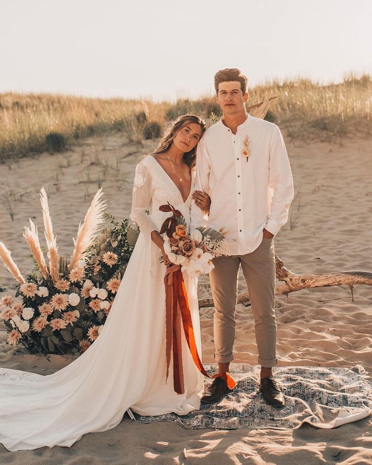 a man and woman standing on top of a sandy beach next to eachother