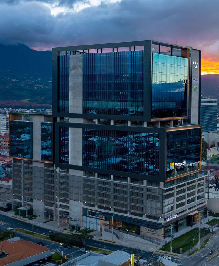 an aerial view of a large building in the middle of a city with mountains in the background