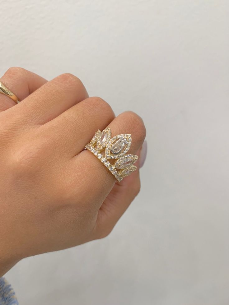 a woman's hand wearing a gold ring with two leaves on it and diamonds in the middle