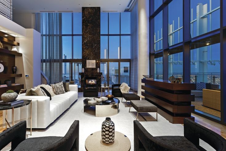 a living room filled with lots of furniture and tall windows overlooking the cityscape